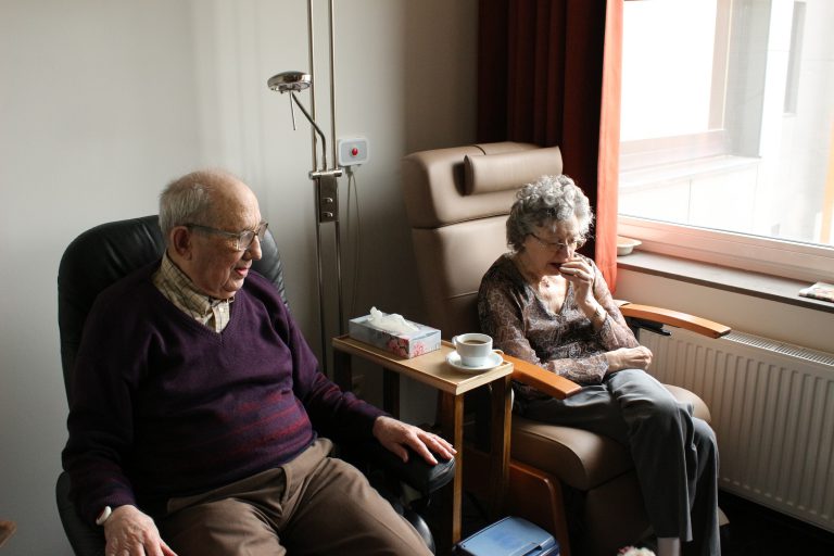 couple sitting side by side near panel radiator