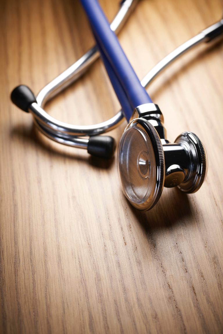 shallow focus photo of blue and gray stethoscope on brown wooden table