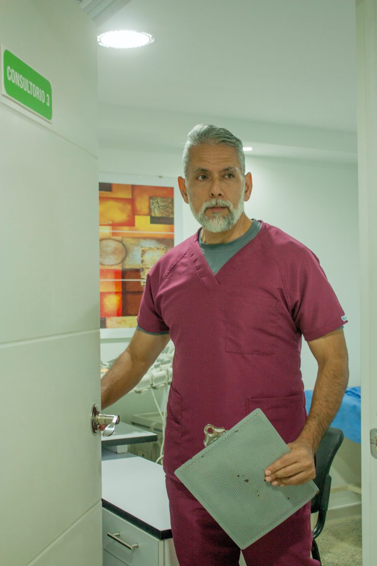 man in blue crew neck t-shirt standing near white wooden cabinet